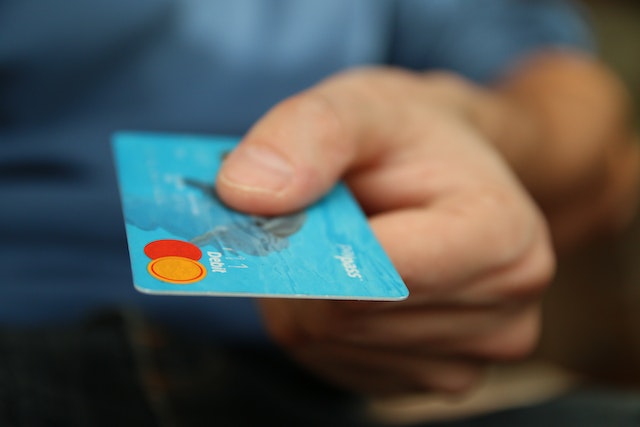 person holding out a blue credit card